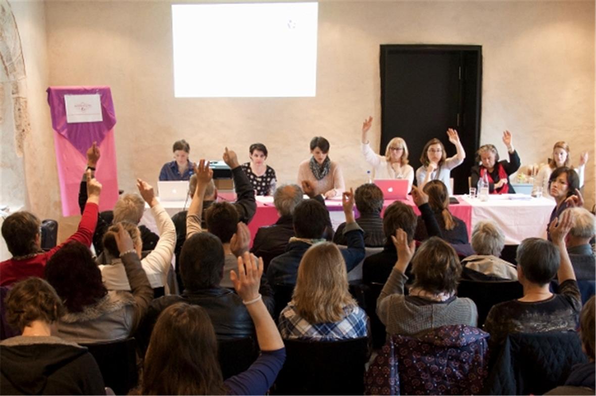 Abstimmende Mitglieder und im Hintergrund die Verwaltung der Genossenschaft.