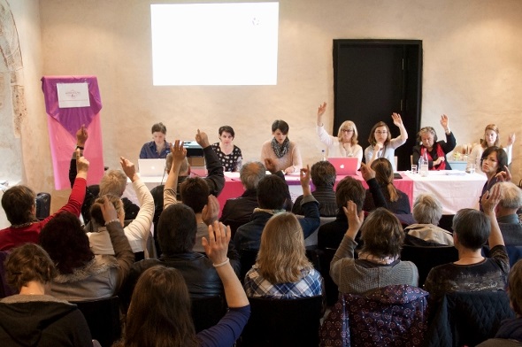 Abstimmende Mitglieder und im Hintergrund die Verwaltung der Genossenschaft.