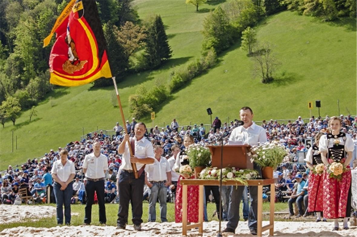 Am Rednerpult OK-Präsident Res Gobeli mit Fähnrich Adrian Gobeli, flankiert von ...