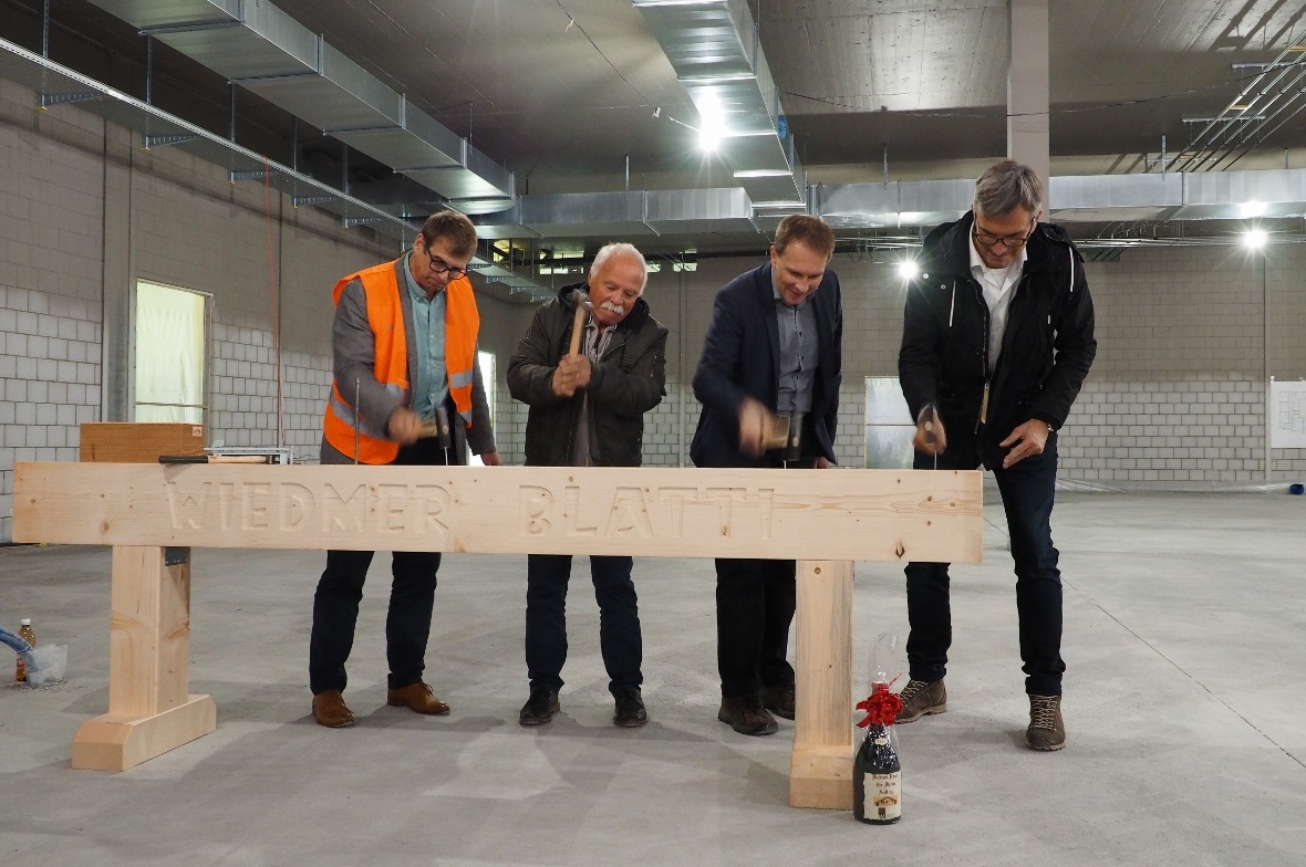 Aufrichtefeier in der Migros Zweisimmen: Damit die Handwerker etwas zum Lachen haben, müssen die Theoretiker Nägel einschlagen: Norbert Scholz, Gesamtprojektleiter Bau; Ernst Hodel, Gemeinderatspräsident von Zweisimmen; Heinz Rüedi, Leiter Entwicklung, Bau und Betrieb sowie Architekt Heinz Brügger.