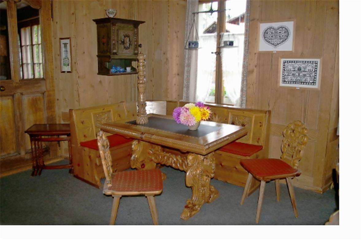 Der Stubentisch mit den Stabellen und Scherenschnitte im Hintergrund.