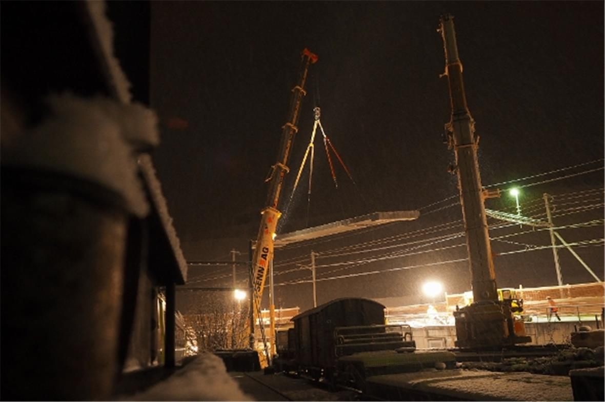 Der zweite Kran nimmt die Brücke dann wieder vom Boden auf und stellt sie an ein...