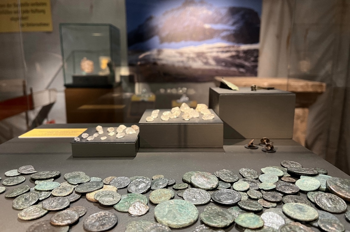 Die Fundstücke: Römermünzen, Bergkristalle, Fragmente einer Kleiderklammer (Fieb...