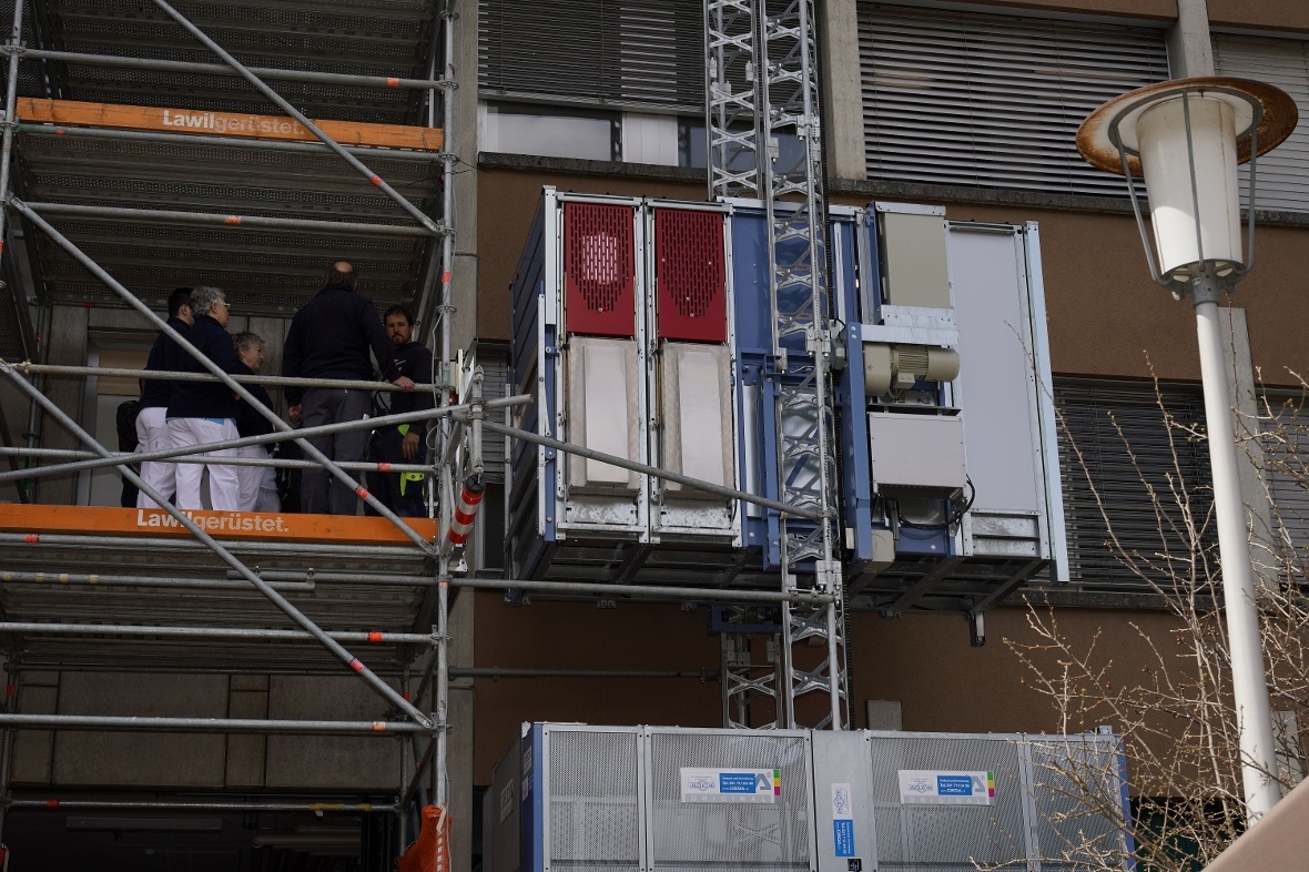 Die Kabine des Aussenlifts ist im ersten Stock angekommen. Über die Gerüstkonstr...