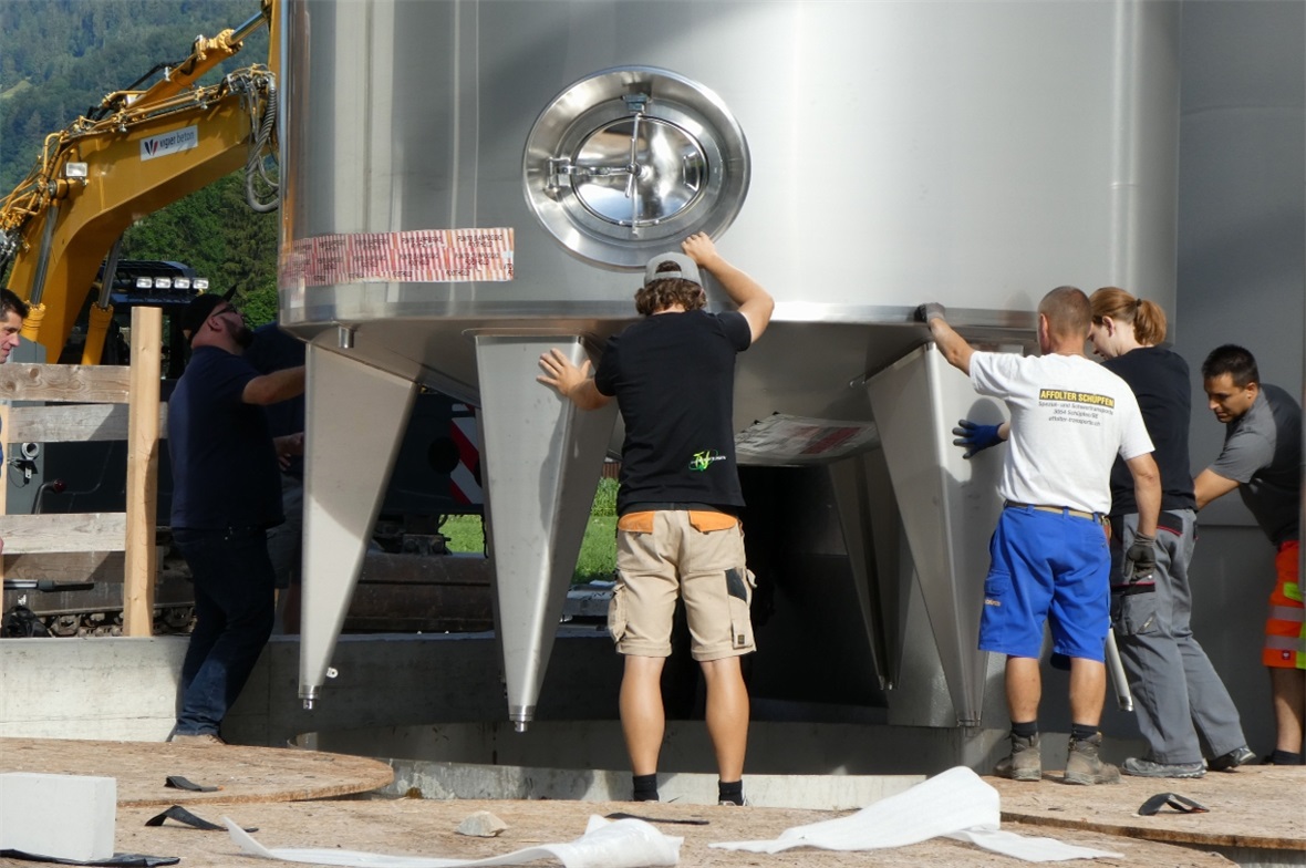 Die Mitarbeiter steuern den Tank präzisein die Grube.