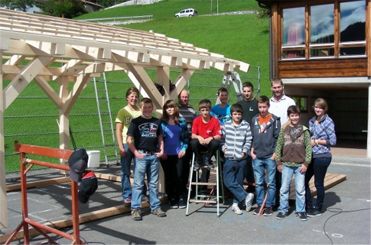 Die Oberstufenklasse mit ihrem Klassenlehrer Jürg Ogi und dem Zimmermann Niklaus Zahler.