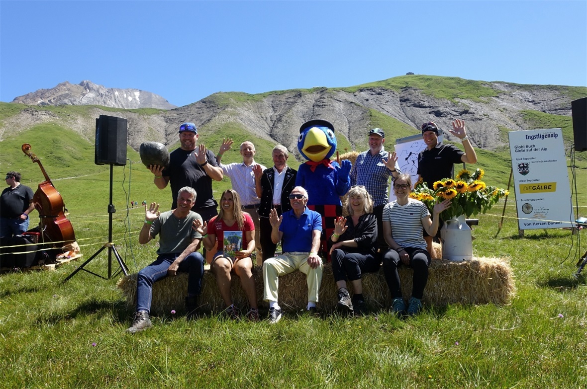 Die vereinte Globi-Familie mit Götti Chrigu Stucki, Texter Jürg Lendenmann, Senn Erich Wäfler, Globi, Zeichner Daniel Frick und Gleitschirmpilot Chrigel Maurer (hinten). Vorne winken Hörbuch-Vertoner Alexius Tschallener, Gotti Joana Hählen, Globi-Stimme Walter Andreas Müller, Globi Verlagsleiterin Gisela Klinkenberg sowie Marketingleiterin Seraina von Känel von den Bergbahnen Engstligenalp.