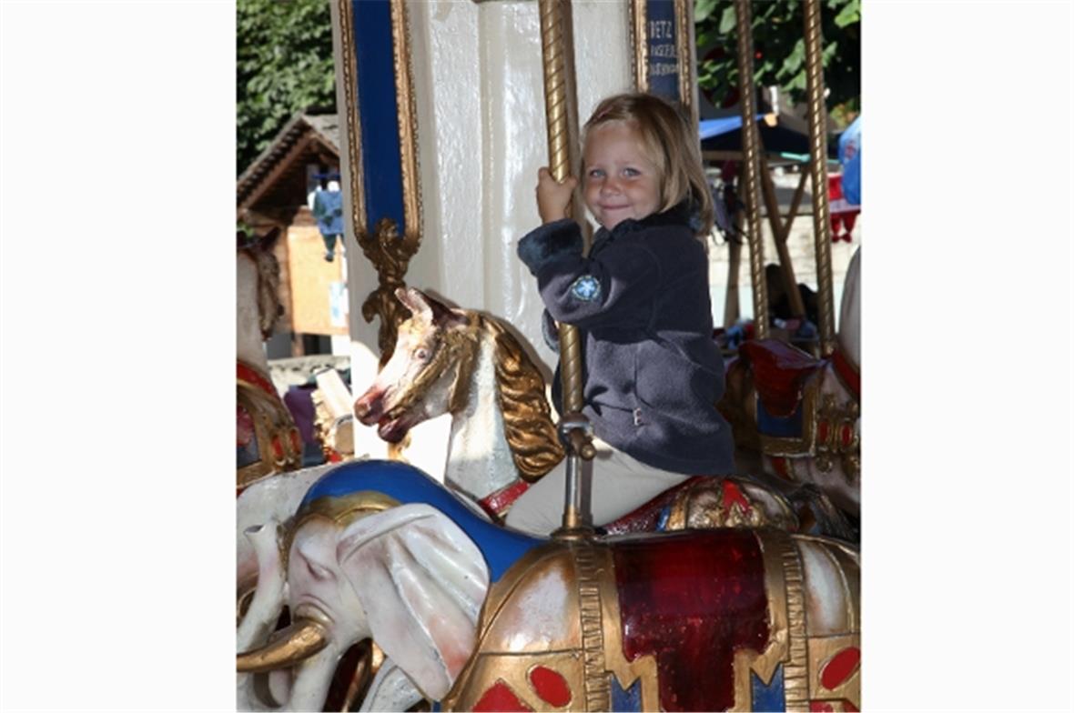 Ein Kinderlächeln auf dem Karrussell.