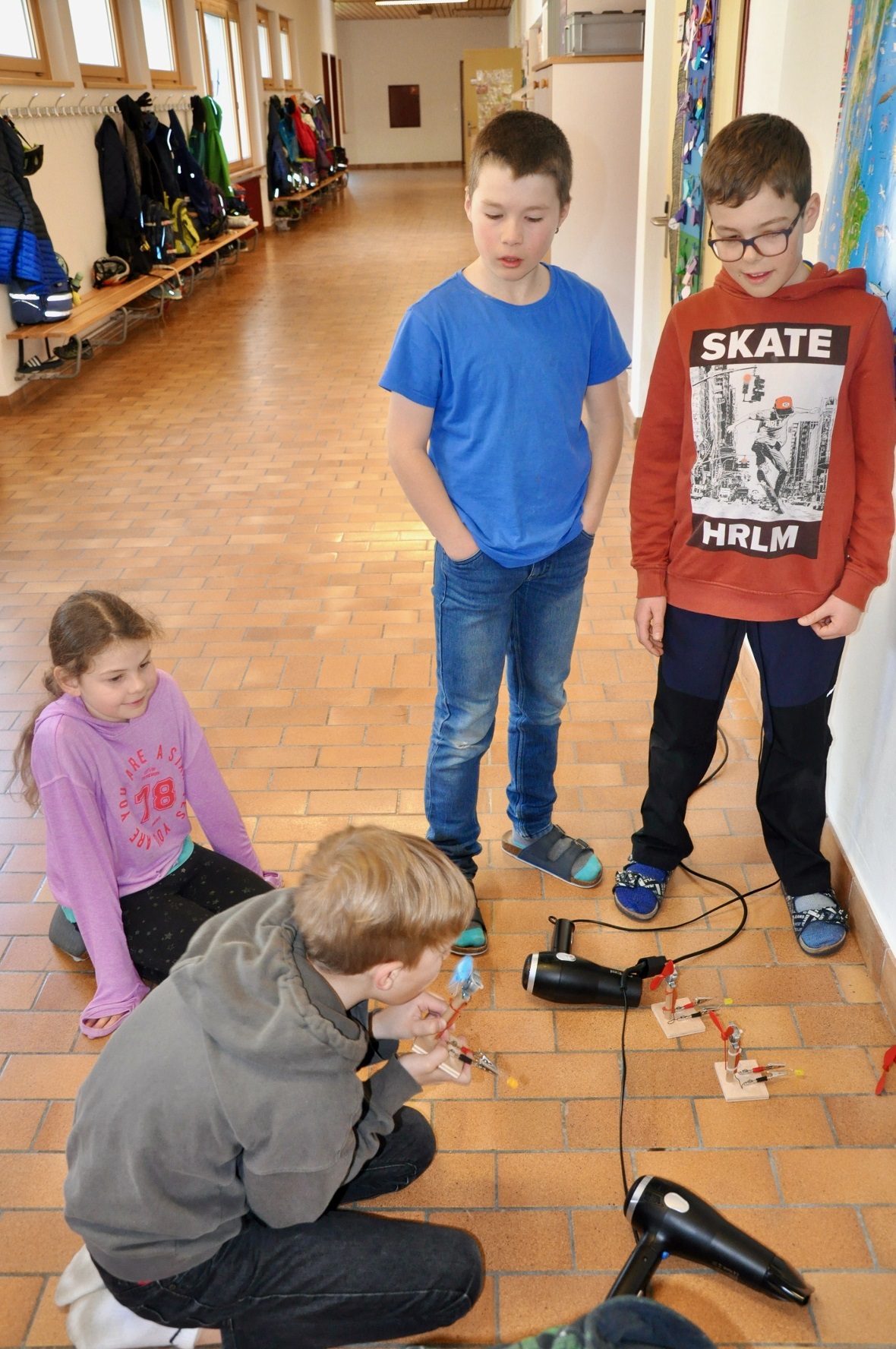 Ein Schüler der 5. Klasse zeigt SuS der 3./4. Klasse wie durch Pusten ein LED-Lä...