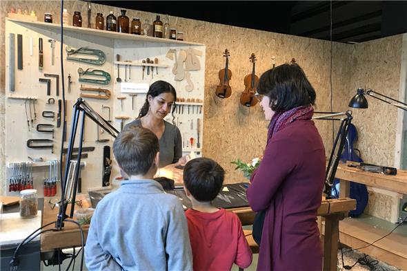 Eine angehende Geigenbauerin erläutert ihr Handwerk.