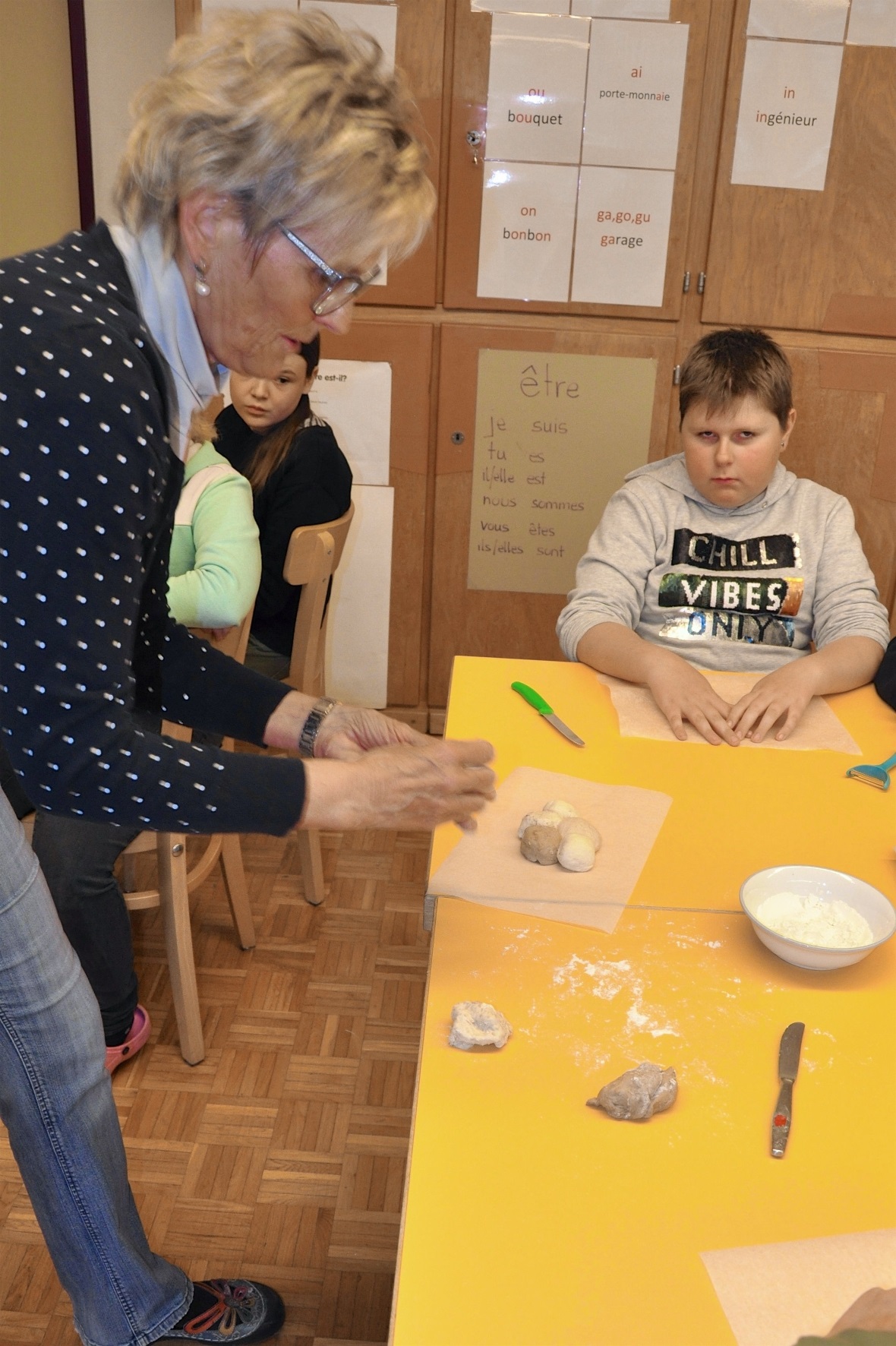 Frau Gerber zeigt den Schülern vor, wie die Partybrote hergestellt werden.