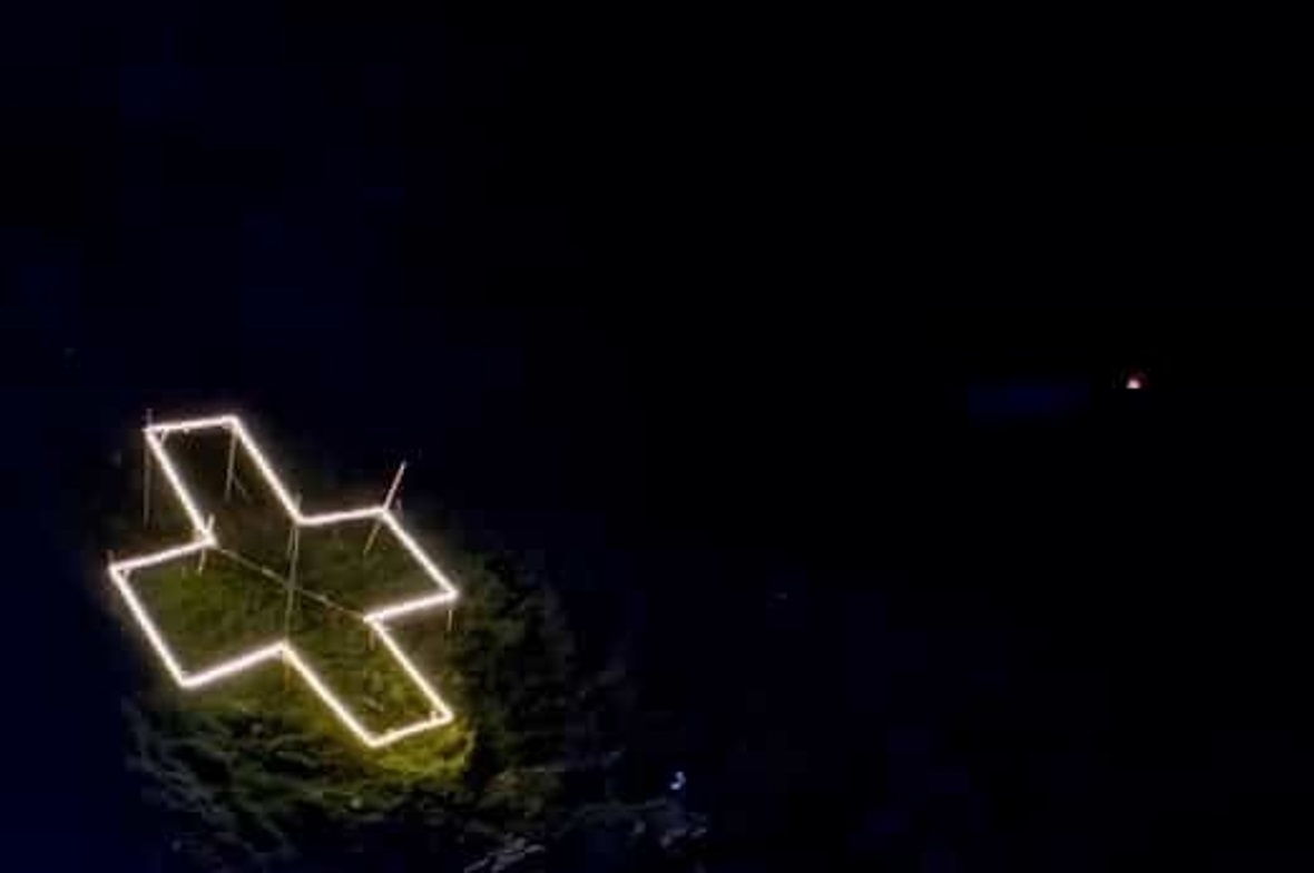 Improvisiert aber erfolgreich: Das LED-Kreuz am Fluesee. Links das Gerüst mit den LED, rechts beleuchtet bei Nacht.