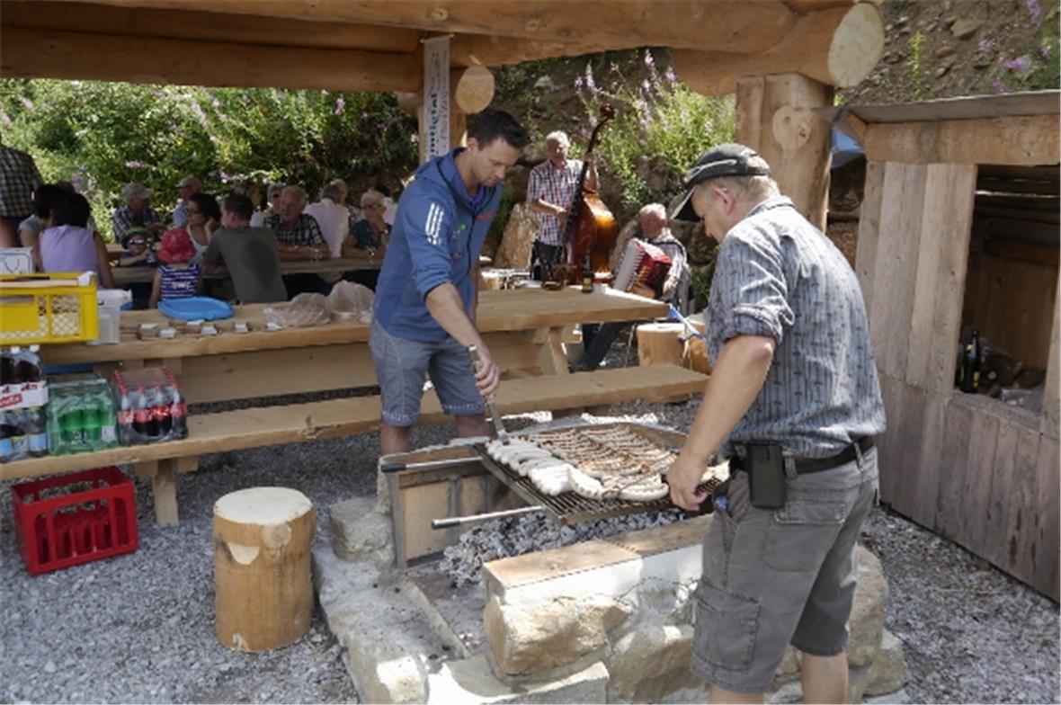 Kilian Wenger und Beat Spring bereiten für die Besucher die Grillwürste zu. Im Hintergrund spielt das Duo Bruno Bähler und Christian Flückiger.