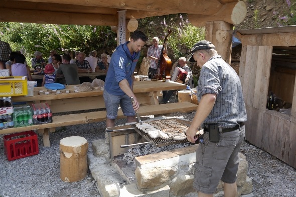 Kilian Wenger und Beat Spring bereiten für die Besucher die Grillwürste zu. Im Hintergrund spielt das Duo Bruno Bähler und Christian Flückiger.