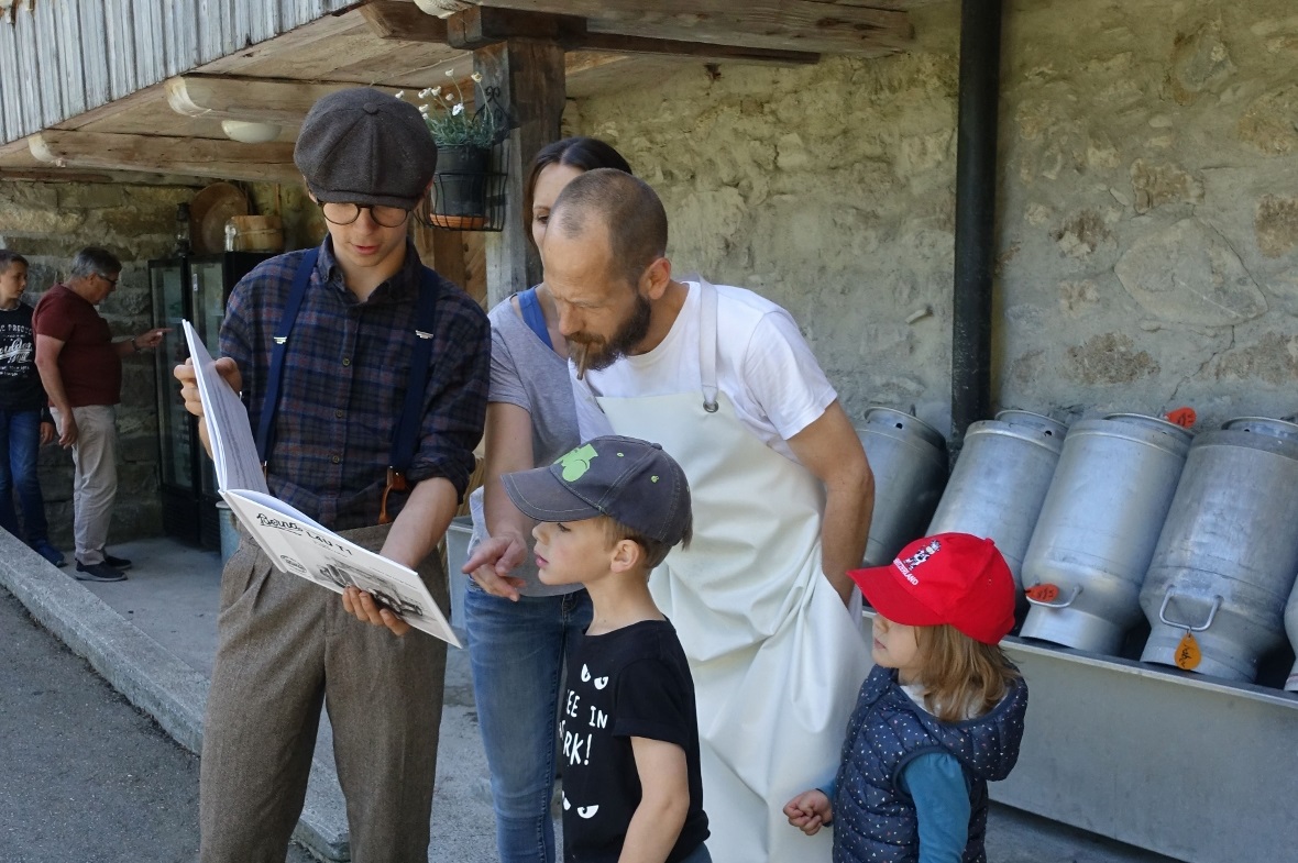 Leonard Riesen zeigt der Käserfamilie Troger das Buch mit dem alten Lastwagen.