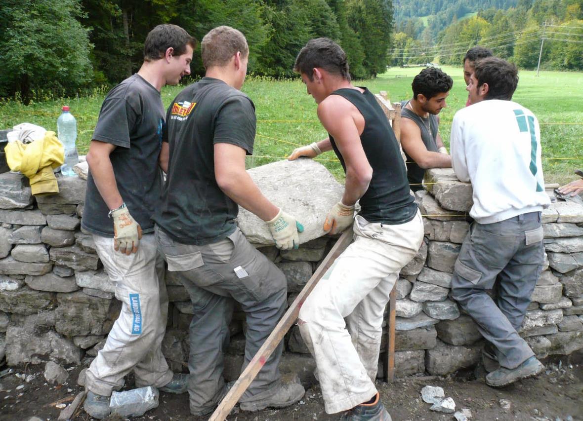 Maurer-Lehrlinge beim Neuaufbau der Trockenmauer.