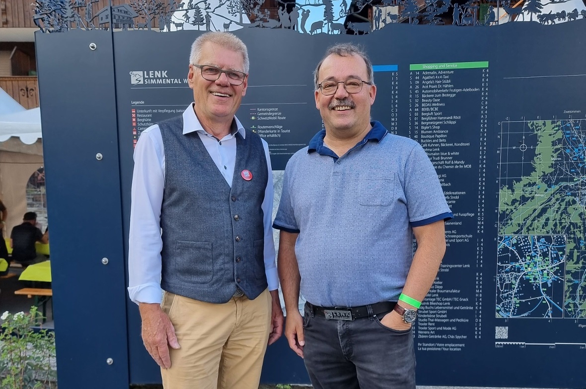 OK-Präsident Hans-Jörg Schneider und Gemeindepräsident René Müller vor der neuen Informationstafel beim Begegnungsplatz im Lenker Dorfkern.