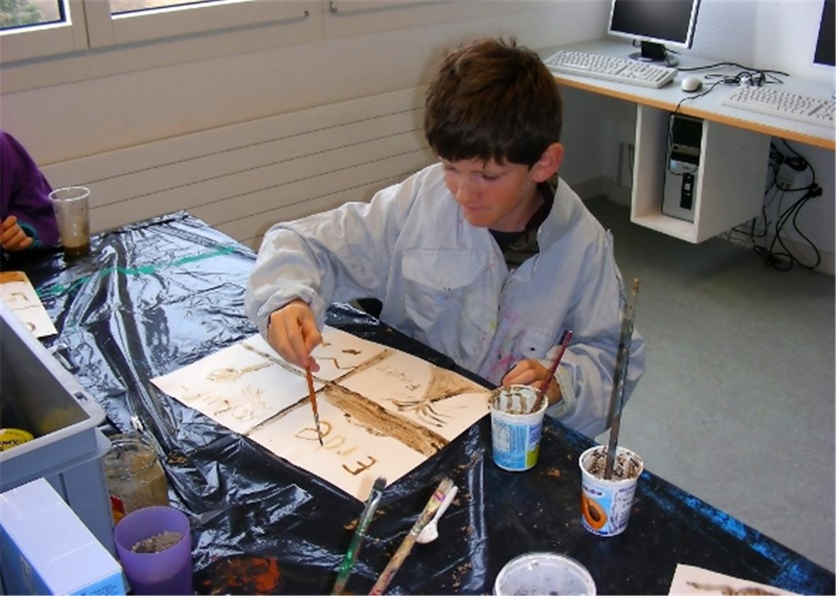 Pascal malt mit Erd-Farbe.