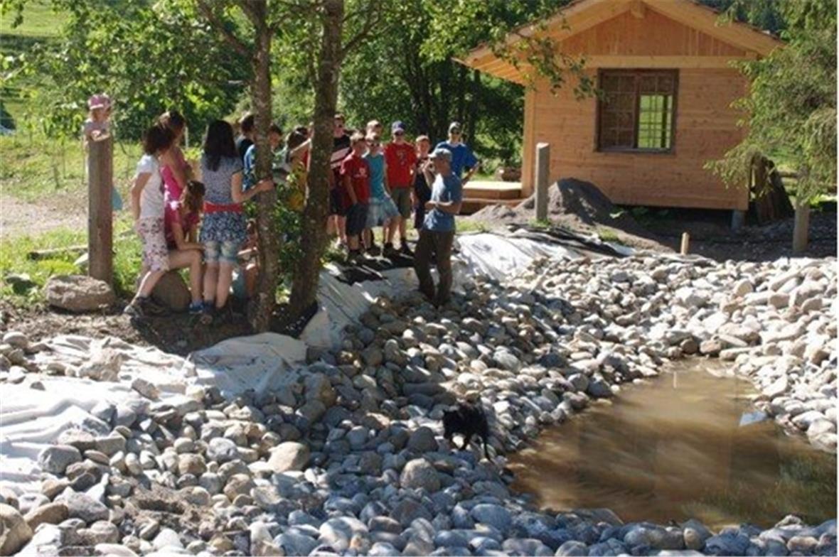 Projektleiter und Animateur Heinz Lerch mit der Schulklasse beim Teich im Hinter...