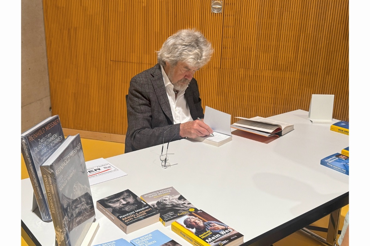 Reinhold Messener beim signieren von Büchern.