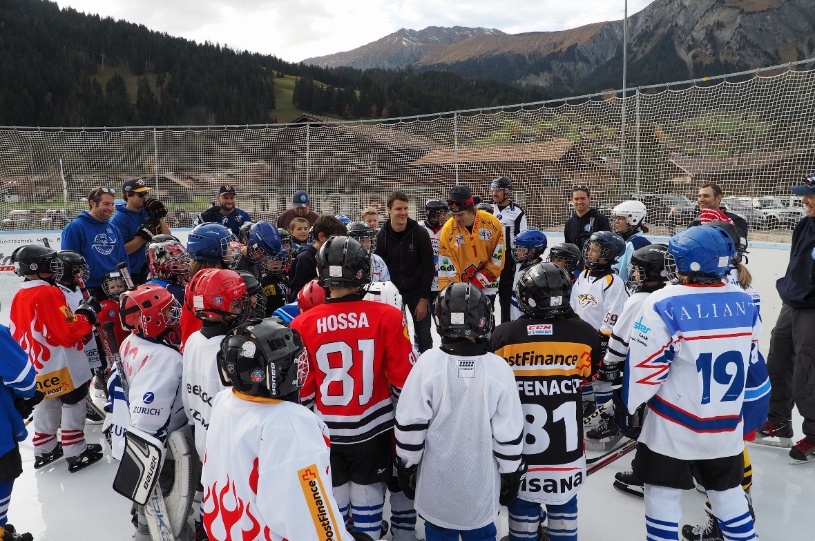 SCB-Spieler Gaëtan Haas und Jonas Hiller vom EHC Biel inmitten der über 50 Kinder, die zum Swiss Ice Hockey Day des EHC Lenk-Zweisimmen kamen.
