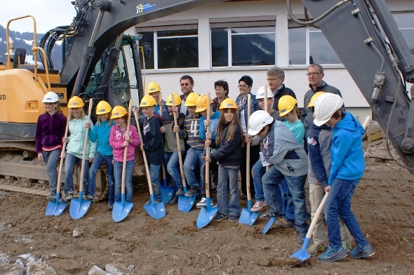 Schulkinder der 5./6. Klasse unterstützen Baukommissionspräsident Albin Buchs, Schulkommissionspräsidentin Pia Perren, Schulleiterin Petra Krebs und die Architekten Hans Grünenwald und Beat Kuhnen beim Spatenstich für das neue Schulhaus.