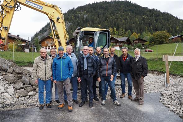 Ueli Gfeller, Markus Mösching, Marc von Felten, Hanspeter Abbühl, Bernhard Riedo, Simon Waldmann, Walter Schläppi, Kurt Trachsel, Christoph Kuhnen, Bruno Kohler und Gottfried Trachsel feierten den Spatenstich der Fernwärme. Die Sekretärin Sandra Mösching durfte für das Foto auf dem Bagger Platz nehmen. Im Hintergrund ist der Rohstoff für die Fernwärme zu sehen – der eigene Püürtwald.
